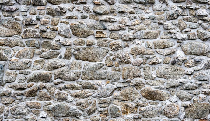 A detailed view of a grey natural stone masonry wall with professional mortar work