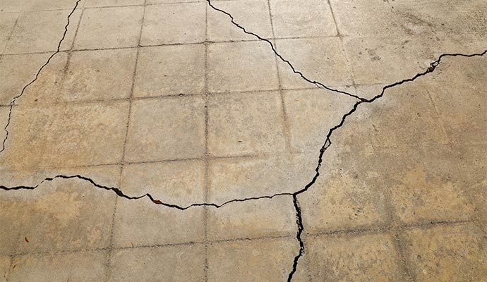 Large structural cracks spreading across a concrete foundation floor