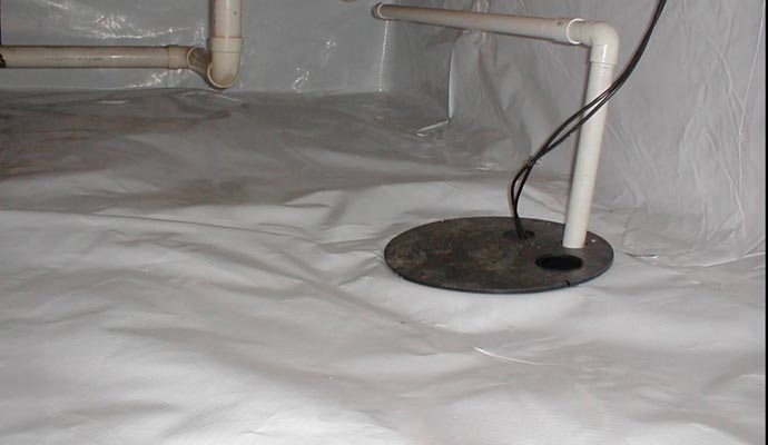 Crawl space sump pump basin with PVC discharge pipe on white vapor barrier