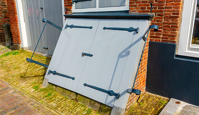 Closed exterior crawl space access doors on brick wall