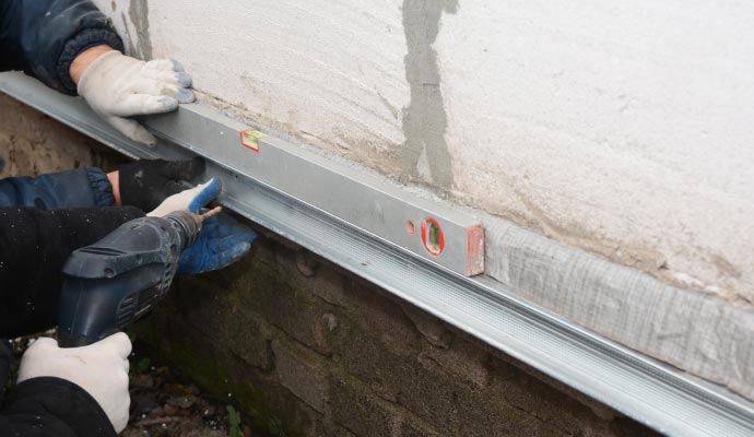 Foundation wall repair with a metal support rail being installed