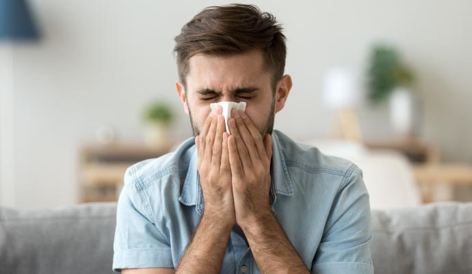 Man sneezing due to an allergic reaction Man sneezing due to an allergic reaction