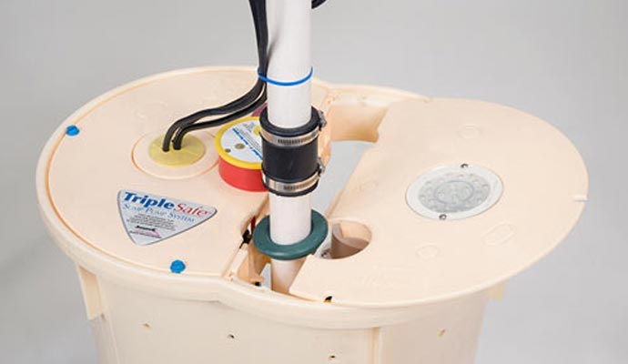 Close-up of TripleSafe sump pump system lid with discharge pipe and wiring